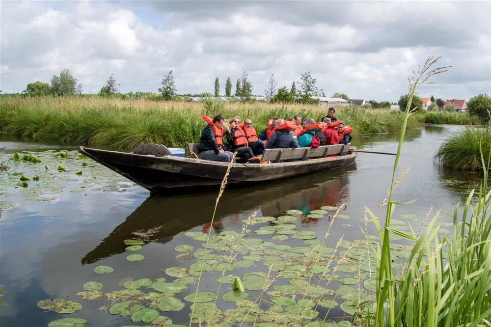 Groupe en gilets orange à bord d'une barque traditionnelle dans les marais audomarois