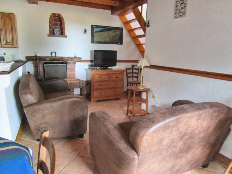Salon du gîte 5 personnes, cheminée en briques, fauteuils et escalier en bois